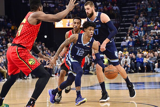 Memphis Grizzlies guard Ja Morant (12) handles the ball between Atlanta Hawks forward Bruno Fernando, left, guard Jeff Teague, center, and Grizzlies center Jonas Valanciunas (17) in the second half of an NBA basketball game Saturday, March 7, 2020, in Memphis, Tenn. (AP Photo/Brandon Dill)