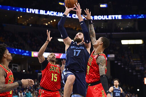 Memphis Grizzlies center Jonas Valanciunas (17) shoots between Atlanta Hawks guard Vince Carter (15) and forward John Collins (20) in the second half of an NBA basketball game Saturday, March 7, 2020, in Memphis, Tenn. (AP Photo/Brandon Dill)