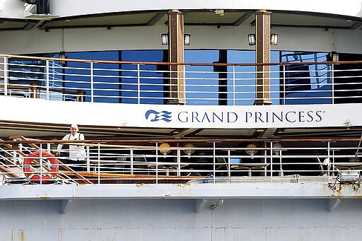 A crewman stands aboard the Grand Princess as it maintains a holding pattern about 25 miles off the coast of San Francisco on Sunday, March 8, 2020. The cruise ship is scheduled to dock at the Port of Oakland on Monday for COVID-19 quarantine after 21 people tested positive for the virus. (AP Photo/Noah Berger)