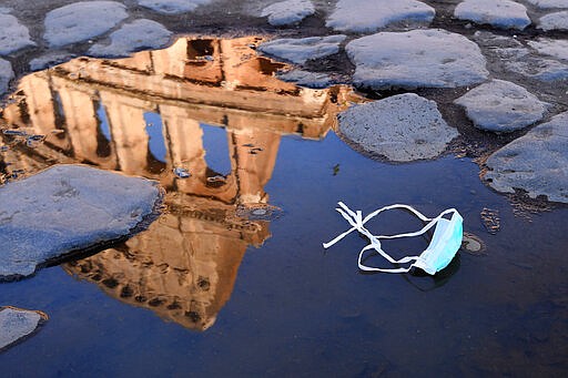 The Colosseum, that will be closed following the government's new prevention measures on public gatherings, is reflected in a puddle where a face mask was left, in Rome, Sunday, March 8, 2020. Italy announced a sweeping quarantine early Sunday for its northern regions, igniting travel chaos as it restricted the movements of a quarter of its population in a bid to halt the new coronavirus' relentless march across Europe. (Alfredo Falcone/LaPresse via AP)