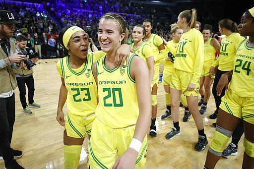 Oregon's Minyon Moore (23) and Sabrina Ionescu (20) walk off the court after defeating Arizona in an NCAA college basketball game in the semifinal round of the Pac-12 women's tournament Saturday, March 7, 2020, in Las Vegas. (AP Photo/John Locher)