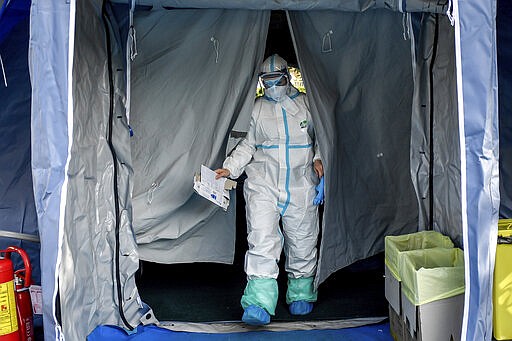 Medical personnel leaves one of the emergency structures that were set up to ease procedures outside the hospital of Brescia, Northern Italy, Tuesday, March 10, 2020. For most people, the new coronavirus causes only mild or moderate symptoms, such as fever and cough. For some, especially older adults and people with existing health problems, it can cause more severe illness, including pneumonia. (Claudio Furlan/LaPresse via AP)