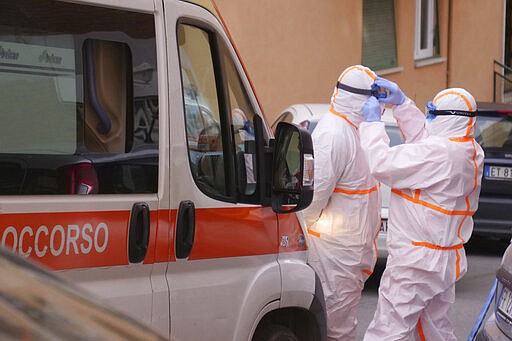 Personnel of a special ambulance for the transportation of the new Coronavirus patients, finish dressing up before intervening in Rome Tuesday, March 10, 2020. For most people, the new coronavirus causes only mild or moderate symptoms, such as fever and cough. For some, especially older adults and people with existing health problems, it can cause more severe illness, including pneumonia. (AP Photo/Paolo Santalucia)