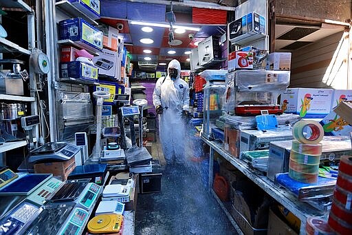 A Civil Defense worker wearing a protective suit sprays disinfectant as a precaution against the coronavirus in the main market, Baghdad, Iraq, Tuesday, March 10, 2020. For most people, the new coronavirus causes only mild or moderate symptoms, such as fever and cough. For some, especially older adults and people with existing health problems, it can cause more severe illness, including pneumonia. (AP Photo/Hadi Mizban)