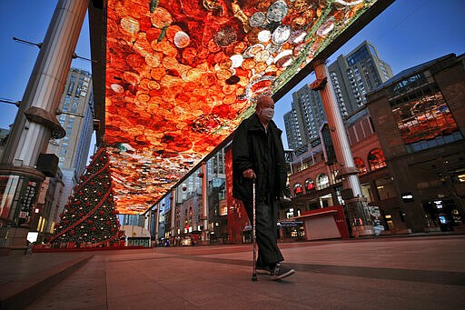 A man walks with a stick passes by a huge screen showing a colourful art at a quiet shopping mall in Beijing, Tuesday, March 10, 2020. China's president Xi Jinping visited the center of the global virus outbreak Tuesday as Italy began a sweeping nationwide travel ban and people worldwide braced for the possibility of recession. For most people, the new coronavirus causes only mild or moderate symptoms, such as fever and cough. For some, especially older adults and people with existing health problems, it can cause more severe illness, including pneumonia. (AP Photo/Andy Wong)