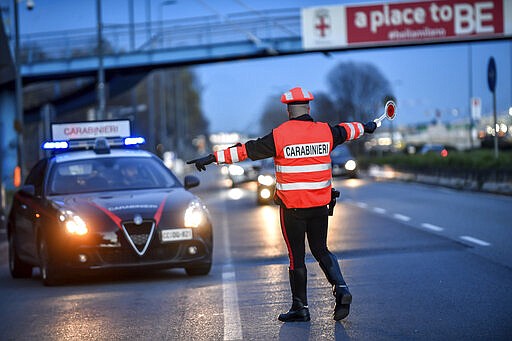 A policeman checks cars entering Milan, Northern Italy, Tuesday, March 10, 2020. People moving from one place to another must certificate they are doing it for work or important personal or health reasons, following the latest measures to slow down the diffusion of the new Coronavirus. For most people, the new coronavirus causes only mild or moderate symptoms, such as fever and cough. For some, especially older adults and people with existing health problems, it can cause more severe illness, including pneumonia. (Claudio Furlan/LaPresse via AP)