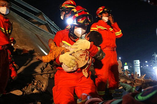 In this March 8, 2020, photo, rescuers pull a young child out from the rubbles of a collapsed hotel on a stretcher in Quanzhou, southeast China's Fujian Province. Several have been killed and others trapped when in the collapsed Chinese hotel that was being used to isolate people who had arrived from other parts of China hit hard by the coronavirus outbreak, authorities said Sunday. (Chinatopix Via AP)