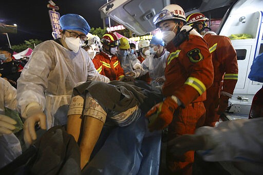 In this March 9, 2020, photo released by Xinhua News Agency, rescuers carry a woman pulled from the rubbles of a collapsed hotel to an ambulance in Quanzhou, southeast China's Fujian Province. Several have been killed and others trapped when in the collapsed Chinese hotel that was being used to isolate people who had arrived from other parts of China hit hard by the coronavirus outbreak, authorities said Sunday. (Zeng Demeng/Xinhua via AP)