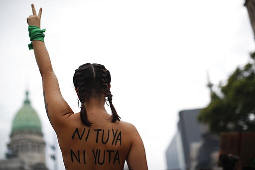 A woman makes the Victory sign in front of the Congress during a march to commemorate the International Women's Day in Buenos Aires, Argentina, Monday, March 9, 2020.(AP Photo/Natacha Pisarenko)