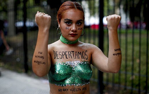 A woman poses for a photo with the words &quot;We woke up&quot; written in Spanish on her chest during a march to commemorate International Women's Day in Buenos Aires, Argentina, Monday, March 9, 2020. (AP Photo/Natacha Pisarenko)