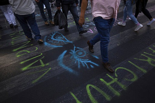 Pedestrian walks on a street painted with graffiti in reference to the International Women's Day strike &quot;A Day Without Women&quot; in Mexico City, Monday, March 9, 2020. Thousands of women across Mexico went on strike after an unprecedented number of girls and women hit the streets to protest rampant gender violence on International Women's Day. (AP Photo/Fernando Llano)