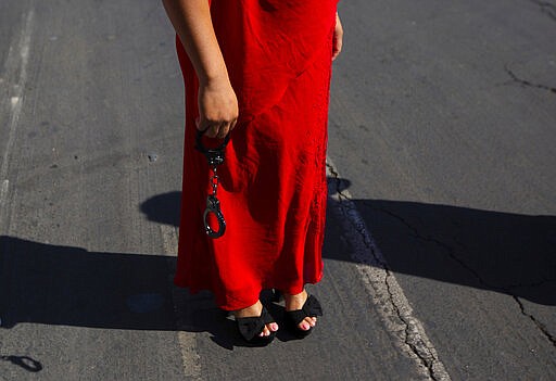 A demonstrator wears a red dress as she holds a pair of handcuffs during the International Women's Day strike &quot;A Day Without Women&quot; at Zocalo square in Mexico City, Monday, March 9, 2020. Thousands of women across Mexico went on strike after an unprecedented number of girls and women hit the streets to protest rampant gender violence on International Women's Day. (AP Photo/Fernando Llano)