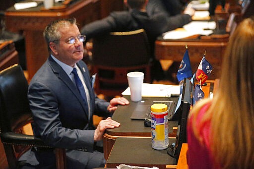 A container of disinfectant wipes sits next to the desk of Rep. Jerome Zeringue, R-Houma, seated left, during the start of the 2020 general legislative session in Baton Rouge, La., Monday, March 9, 2020. Gov. John Bel Edwards announced at the session that the state's first confirmed case of the COVID-19 Coronavirus was discovered today in Jefferson Parish. (AP Photo/Gerald Herbert)