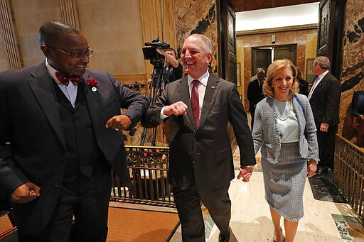 Louisiana Gov. John Bel Edwards, center, bumps elbows with state Rep. Patrick Jefferson, D-Homer, instead of his traditional handshake, as a precaution against the COVID-9 Coronavirus, as he walks down the aisle of the House Chambers for the opening of the 2020 general legislative session in Baton Rouge, La., Monday, March 9, 2020. Edwards subsequently announced to the legislature that Louisiana today had its first confirmed case of the virus in Jefferson Parish. Right is Edwards wife Donna Edwards. (AP Photo/Gerald Herbert)