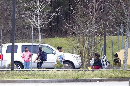 Students wait outside at Woodland Middle School in East Point, Ga., Monday, March 9, 2020. The Fulton County School system has decided to close schools on Tuesday after a teacher tested positive with the coronavirus. The teacher was at Woodland Middle school on Friday. (Alyssa Pointer/Atlanta Journal-Constitution via AP)