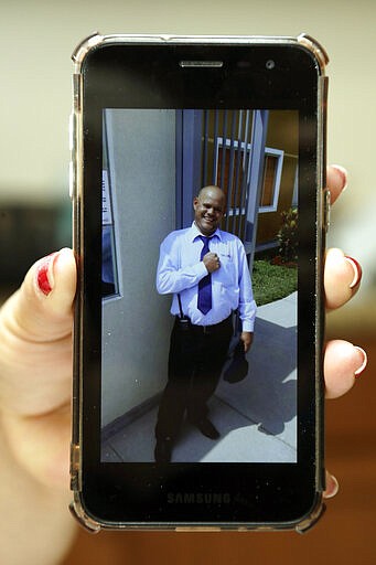 In this Wednesday, Feb. 26, 2020 photo, Yarelis Gutierrez Barrios holds up a cell phone photo at her home in Tampa, Fla., of her partner Roylan Hernandez Diaz, a Cuban asylum seeker who hanged himself in a Louisiana prison.  An Associated Press investigation into Hernandezs death last October found neglect and apparent violations of government policies by jailers under U.S. Immigration and Customs Enforcement.  (AP Photo/Chris O'Meara)