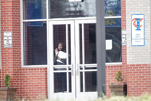 A student waits at the front entrance at Woodland Middle School in East Point, Ga.,Monday, March 9, 2020. The Fulton County School system has decided to close schools on Tuesday after a teacher tested positive with the coronavirus. The teacher was at Woodland Middle school on Friday. (Alyssa Pointer/Atlanta Journal-Constitution via AP)