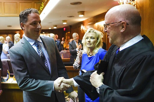 Todd Huston, R-Fishers, left, greets Supreme Court Justice Mark Massa in the House Chamber before being sworn in as Speaker of the House at the Statehouse in Indianapolis, Monday, March 9, 2020. Houston's wife Denise holds the bible to his right. (AP Photo/AJ Mast)