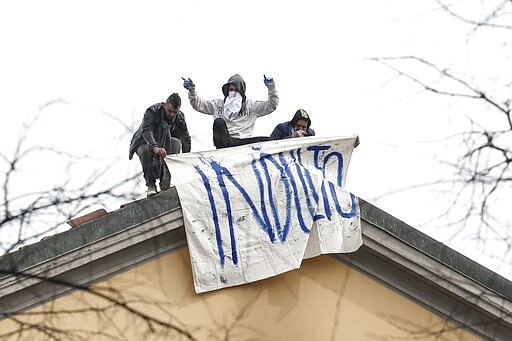 Inmates unfold a banner reading in Italian Pardon as they stage a protest against new rules, including the suspension of relatives' visits, to cope with coronavirus emergency, on the roof of the San Vittore prison in Milan, Italy, Monday, March 9, 2020. Italy took a page from China's playbook Sunday, attempting to lock down 16 million people &#151; more than a quarter of its population &#151; for nearly a month to halt the relentless march of the new coronavirus across Europe. (AP Photo/Antonio Calanni)