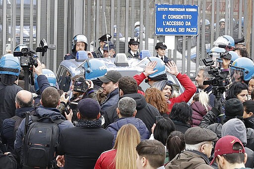 Relatives of Rebibbia prison's inmates face police after inmates staged a protest against new coronavirus containment measures, in Rome, Monday, March 9, 2020. Italian penitentiary police say six inmates protesting coronavirus containment measures at the northern Italian prison of Modena have died after they broke into the infirmary and overdosed on methadone. The protest Sunday in Modena was among the first of more than two-dozen riots at Italy's overcrowded lock-ups that grew Monday. (AP Photo/Andrew Medichini)