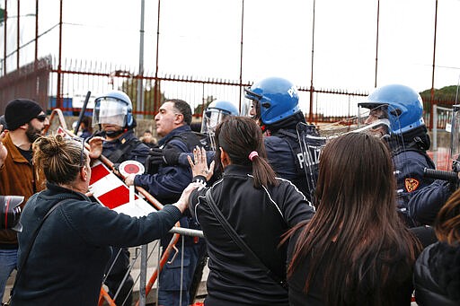 Relatives of Rebibbia prison's inmates face police after inmates staged a protest against new coronavirus containment measures, in Rome, Monday, March 9, 2020. Italian penitentiary police say six inmates protesting coronavirus containment measures at the northern Italian prison of Modena have died after they broke into the infirmary and overdosed on methadone. The protest Sunday in Modena was among the first of more than two-dozen riots at Italy's overcrowded lock-ups that grew Monday. (Cecilia Fabiano/LaPresse via AP)