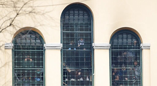 Inmates stand behind bars at the San Vittore prison as protests broke out following restrictions that were imposed on family visits to prevent coronavirus transmissions, in Milan, Italy, Monday, March 9, 2020. Italian penitentiary police say six inmates protesting virus containment measures at the northern Italian prison of Modena have died after they broke into the infirmary and overdosed on methadone. The protest Sunday in Modena was among the first of more than two-dozen riots at Italy's overcrowded lock-ups that grew Monday. (AP Photo/Antonio Calanni)