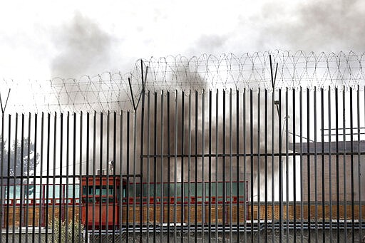 Smoke billows from Rebibbia prison following inmates' protests, in Rome, Monday, March 9, 2020. Italian penitentiary police say six inmates protesting coronavirus containment measures at the northern Italian prison of Modena have died after they broke into the infirmary and overdosed on methadone. The protest Sunday in Modena was among the first of more than two-dozen riots at Italy's overcrowded lock-ups that grew Monday. (Cecilia Fabiano/LaPresse via AP)