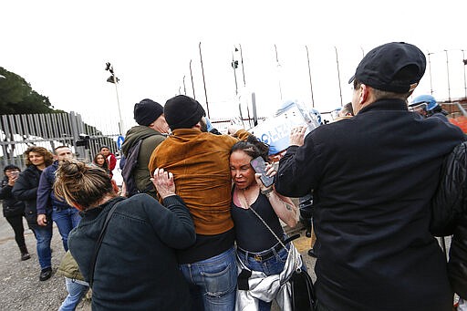 Relatives of Rebibbia prison's inmates face police after inmates staged a protest against new coronavirus containment measures, in Rome, Monday, March 9, 2020. Italian penitentiary police say six inmates protesting coronavirus containment measures at the northern Italian prison of Modena have died after they broke into the infirmary and overdosed on methadone. The protest Sunday in Modena was among the first of more than two-dozen riots at Italy's overcrowded lock-ups that grew Monday. (Cecilia Fabiano/LaPresse via AP)