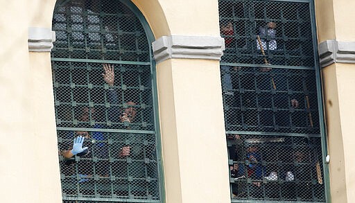 Inmates stand behind bars at the San Vittore prison as protests broke out following restrictions that were imposed on family visits to prevent coronavirus transmissions, in Milan, Italy, Monday, March 9, 2020. Italian penitentiary police say six inmates protesting virus containment measures at the northern Italian prison of Modena have died after they broke into the infirmary and overdosed on methadone. The protest Sunday in Modena was among the first of more than two-dozen riots at Italy's overcrowded lock-ups that grew Monday. (AP Photo/Antonio Calanni)