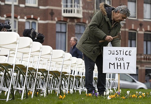 Rob Fredriksz, who lost his son Bryce and his girlfriend Daisy, places a sign next to 298 empty chairs, each chair for one of the 298 victims of the downed Malaysia Air flight MH17, placed in a park opposite the Russian embassy in The Hague, Netherlands, Sunday, March 8, 2020. A missile fired from territory controlled by pro-Russian rebels in Ukraine in 2014, tore the MH17 passenger jet apart killing all 298 people on board. United by grief across oceans and continents, families who lost loved hope that the trial which starts Monday March 9, 2020, will finally deliver them something that has remained elusive ever since: The truth. (AP Photo/Peter Dejong)