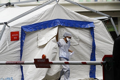 A doctor taking care of people with covid-19 symptoms exits a tent used as a waiting room set up in a courtyard of the Henri Mondor Hospital in Creteil, near Paris, Monday, March 9, 2020. The coronavirus is set to strike a severe blow to French growth in 2020, cutting several decimal points off a figure that may struggle to reach one percent, the finance minister said Monday. (AP Photo/Christophe Ena)