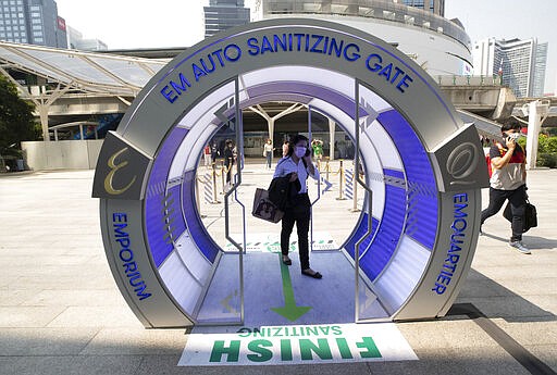 Peoples walk through a 'Auto Sanitizing Gate' in hopes to avoid the spread of the coronavirus outside a shopping mall in Bangkok, Thailand, Monday, March 9, 2020. (AP Photo/Sakchai Lalit)