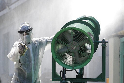 A worker in protective suit controls a large disinfectant spray machine as they sanitize a school that has suspended classes as a precautionary measure against the coronavirus in San Juan city in Manila, Philippines on Monday, March 9, 2020. Philippine President Rodrigo Duterte has declared a state of public health emergency throughout the country after health officials confirmed over the weekend the first local transmission of the new coronavirus. (AP Photo/Aaron Favila)