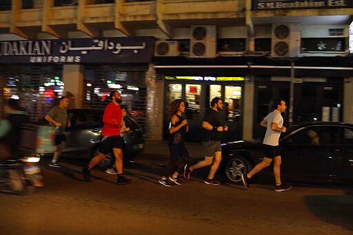 People go on a run in one of Beirut's main nightlife hubs, Lebanon, Monday, March 9, 2020. Lebanon's Tourism ministry ordered bars to close until March 15, and called on restaurants to avoid hosting live events, part of its efforts to contain the spread of coronavirus. Lebanon has at least 41 confirmed cases infected with the virus. The new decision comes after an earlier one asking nightclubs to shut down, a significant move in the country that prided itself in a bustling nightlife despite experiencing several wars. (AP Photo/Bilal Hussein)