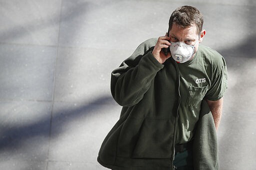 A pedestrian wears a face mask in the World Financial Center complex, Monday, March 9, 2020, in New York. New York continued grappling Monday with the new coronavirus, as case numbers, school closings and other consequences grew. (AP Photo/John Minchillo)