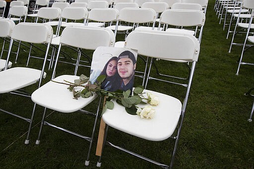 A picture of Bryce Fredriksz and his girlfriend Daisy is placed amidst 298 empty chairs, each chair for one of the 298 victims of the downed Malaysia Air flight MH17, in a park opposite the Russian embassy in The Hague, Netherlands, Sunday, March 8, 2020. A missile fired from territory controlled by pro-Russian rebels in Ukraine in 2014, tore the MH17 passenger jet apart killing all 298 people on board. United by grief across oceans and continents, families who lost loved hope that the trial which starts Monday March 9, 2020, will finally deliver them something that has remained elusive ever since: The truth. (AP Photo/Peter Dejong