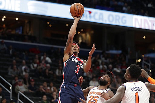 Washington Wizards' Bradley Beal (3) shoots over New York Knicks' Reggie Bullock (25) and Bobby Portis (1) during the second half of an NBA basketball game Tuesday, March 10, 2020, in Washington. (AP Photo/Luis M. Alvarez)