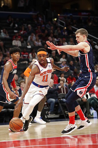 New York Knicks' Frank Ntilikina (11) drives past Washington Wizards' Moritz Wagner, right, during the first half of an NBA basketball game Tuesday, March 10, 2020, in Washington. (AP Photo/Luis M. Alvarez)