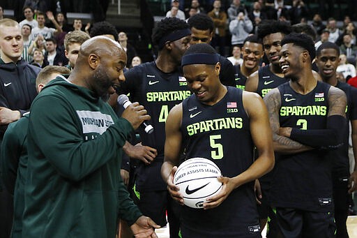 FILE - In this Jan. 17, 2020, file photo, former Michigan State guard Mateen Cleaves, left, presents guard Cassius Winston with a commemorative basketball after Winston broke Cleaves all time Big Ten and Michigan State records, after an NCAA college basketball game against Wisconsin in East Lansing, Mich. Winston was selected to the Associated Press All-Big Ten team selected Tuesday, March 10, 2020. (AP Photo/Carlos Osorio, File)