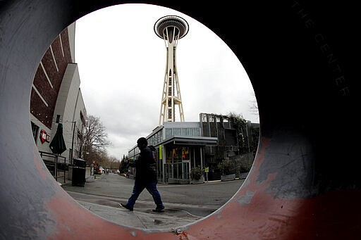 In this March 6, 2020 photo, the Space Needle is seen through the round opening of a sculpture at the Seattle Center in Seattle. King County has become the epicenter of the outbreak of the COVID-19 coronavirus in the U.S., and local businesses are bracing for the cascading impacts of losing customers for an indeterminate amount of time. (AP Photo/Ted S. Warren)