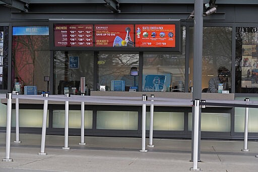 In this March 6, 2020 photo, a person waits for customers as they work in the ticket office for the Space Needle and other attractions at the Seattle Center in Seattle. King County has become the epicenter of the outbreak of the COVID-19 coronavirus in the U.S., and local businesses are bracing for the cascading impacts of losing business from customers and tourists for an indeterminate amount of time. (AP Photo/Ted S. Warren)