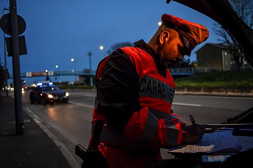 A policeman checks cars entering Milan, Northern Italy, Tuesday, March 10, 2020. People moving from one place to another must certificate they are doing it for work or important personal or health reasons, following the latest measures to slow down the diffusion of the new Coronavirus. For most people, the new coronavirus causes only mild or moderate symptoms, such as fever and cough. For some, especially older adults and people with existing health problems, it can cause more severe illness, including pneumonia. (Claudio Furlan/LaPresse via AP)