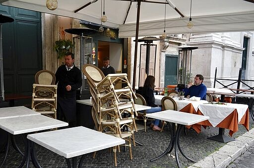 Waiters pile up chairs and prepare to close, according to the Italian government measures to slow down the diffusion of the new Coronavirus, at an hour when normally they warm up for the maximum affluence of customers, in Rome's Piazza Navona, Tuesday, March 10, 2020. For most people, the new coronavirus causes only mild or moderate symptoms, such as fever and cough. For some, especially older adults and people with existing health problems, it can cause more severe illness, including pneumonia. (AP Photo/Andrew Medichini)