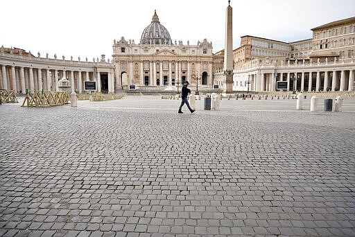 An Italian police officer walks in an empty St. Peter's Square after the Vatican erected a new barricade at the edge of the square, in Rome, Tuesday, March 10, 2020. Italy entered its first day under a nationwide lockdown after a government decree extended restrictions on movement from the hard-hit north to the rest of the country to prevent the spreading of coronavirus.  (AP Photo/Andrew Medichini)