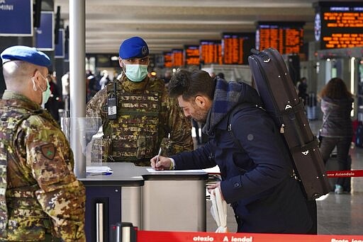 A traveler fills out a form at a check point set up by border police inside Rome's Termini train station, Tuesday, March 10, 2020. In Italy the government extended a coronavirus containment order previously limited to the country&#146;s north to the rest of the country beginning Tuesday, with soldiers and police enforcing bans. (AP Photo/Andrew Medichini)