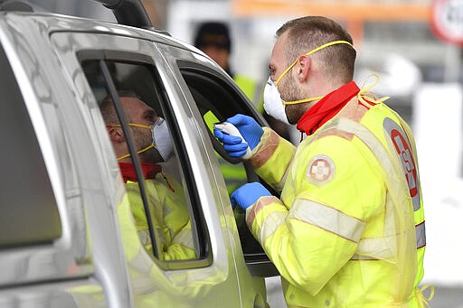 A member of the medical staff measures the temperature of a traveller at a autobahn park place near Gries am Brenner, Austrian province of Tyrol, at border crossing with Italy on Tuesday, March 10, 2020. Austria authorities started on random checks of arriving vehicles at the border crossings with Italy in reaction to the outbreak of the new coronavirus in Europe, particularly in Italy. As part of the move, officials measure the temperatures of some passengers in cars, trucks and buses. For most people, the new coronavirus causes only mild or moderate symptoms, such as fever and cough. For some, especially older adults and people with existing health problems, it can cause more severe illness, including pneumonia. (AP Photo/Kerstin Joensson )