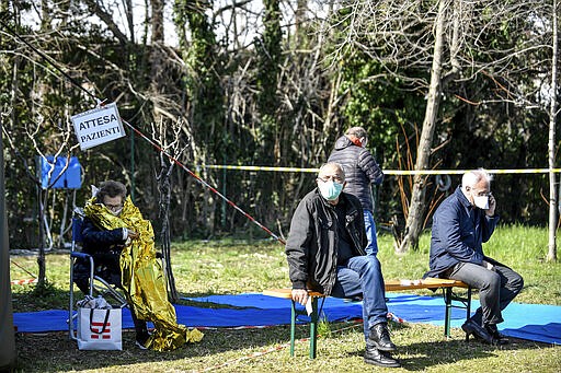 Elderly patients wait to be attended in one of the emergency structures that were set up to ease procedures outside the hospital of Brescia, Northern Italy, Tuesday, March 10, 2020. For most people, the new coronavirus causes only mild or moderate symptoms, such as fever and cough. For some, especially older adults and people with existing health problems, it can cause more severe illness, including pneumonia. (Claudio Furlan/LaPresse via AP)