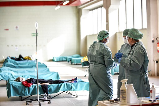 Medical personnel work inside one of the emergency structures that were set up to ease procedures at the hospital of Brescia, Northern Italy, Tuesday, March 10, 2020. For most people, the new coronavirus causes only mild or moderate symptoms, such as fever and cough. For some, especially older adults and people with existing health problems, it can cause more severe illness, including pneumonia. (Claudio Furlan/LaPresse via AP)