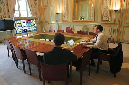 French President Emmanuel Macron and EU adviser Clement Beaune, front, attend a vide conference at the Elysee Palace Tuesday, March 10, 2020 in Paris. In a rare event, the EU's presidents and prime ministers have decided to hold a video-conference summit at around to coordinate efforts to respond to the coronavirus outbreak that has seen a national lock-down imposed in member state Italy. For most people, the new coronavirus causes only mild or moderate symptoms, such as fever and cough. For some, especially older adults and people with existing health problems, it can cause more severe illness, including pneumonia.(AP Photo/Michel Euler, Pool)