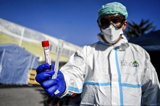 A medical personnel holds a kit for the test for Coronavirus outside one of the emergency structures that were set up to ease procedures outside the hospital of Brescia, Northern Italy, Tuesday, March 10, 2020. For most people, the new coronavirus causes only mild or moderate symptoms, such as fever and cough. For some, especially older adults and people with existing health problems, it can cause more severe illness, including pneumonia. (Claudio Furlan/LaPresse via AP)